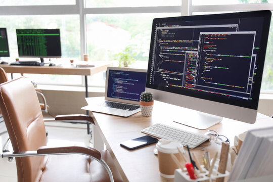 Computer monitor with programming code at programmer's workplace in office