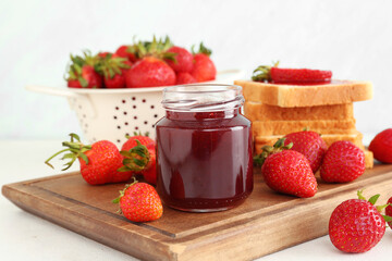 Jar of sweet strawberry jam and fresh berries on table