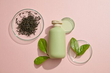 Glass petri dish of dried green tea leaves displayed with a bottle with empty label. Green tea (Camellia sinensis) contains a type of polyphenol called a catechin