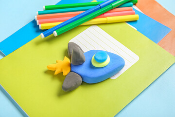 Rocket made of plasticine with stationery on blue background