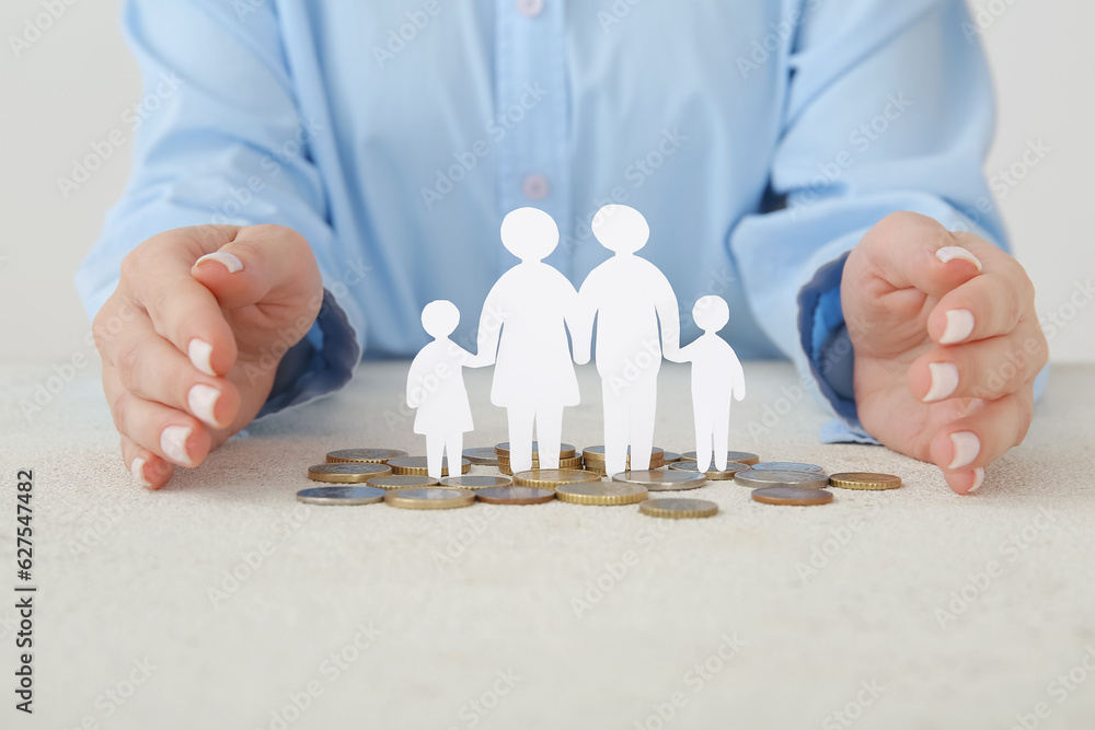 Wall mural woman with figures of family and coins on light table. savings concept