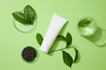 Fresh and dried green tea leaves displayed on green background with unbranded tube. People used...