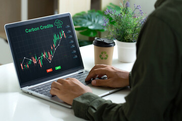 carbon credit concept. Trader using a laptop to trade carbon credit on an application. carbon etf to invest in sustainable business. green climate funds investment. Net zero emission.Clean technology