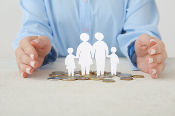 Woman with figures of family and coins on light table. Savings concept