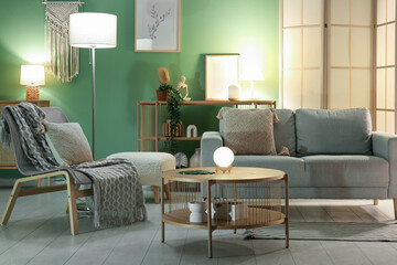 Interior of living room with grey sofa, armchair, coffee table and glowing lamps