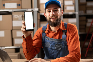 Warehouse software concept. Phone with white screen in warehouse workers hands. Storage and...