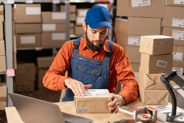 Warehouse worker applying shipping label on parcel boxes