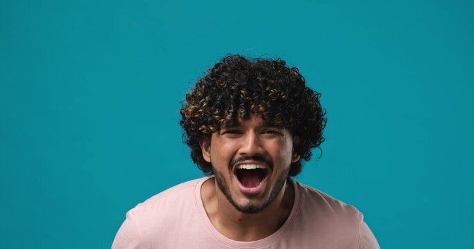 Handsome indian man scream yell close up standing isolated on blue studio background