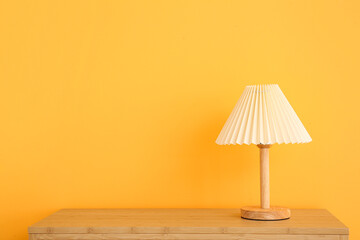 Lamp on wooden table near orange wall