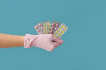 Female doctor's hand with pills in blister packs on blue background