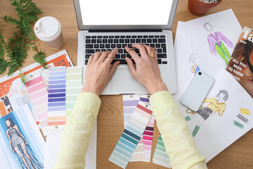 Fashion designer working at table with mobile phone, cup of coffee, color swatches and laptop