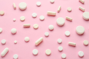 Many different pills on pink background