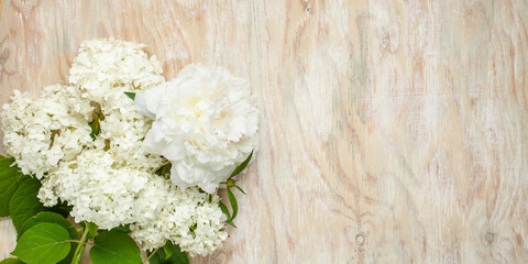 A bouquet of white flowers of hydrangea and peony on a wooden background. Top view