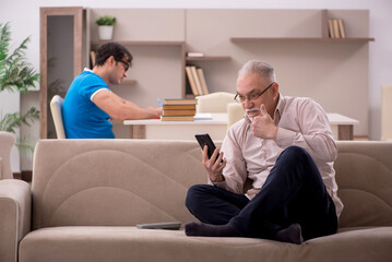 Obraz premium Young male student and his grandfather at home