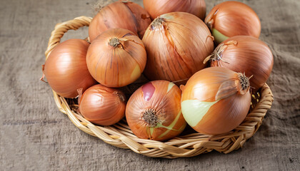A lot of onions in a basket on a textural background. Vegetables in a basket in the form of onions. Harvest onions on burlap.