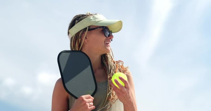 Portrait pickle ball player, woman playing pickleball game, hitting pickleball yellow ball with paddle, outdoor sport leisure activity.