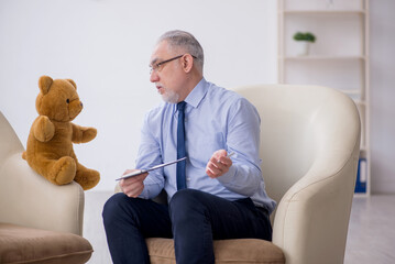 Old male psychologist and soft bear in the room