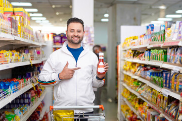 Indian man showing bottle at grocery shop.