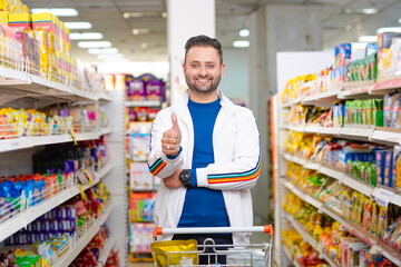 Young indian man showing thumps up at grocery shop.