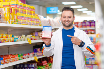 Young indian man showing packets at grocery shop.