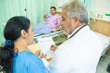 Fototapeta premium Doctor writing medical detail in report after examination to patient