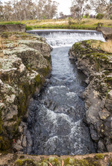 Channeled water flowing from a weir and then between rock walls
