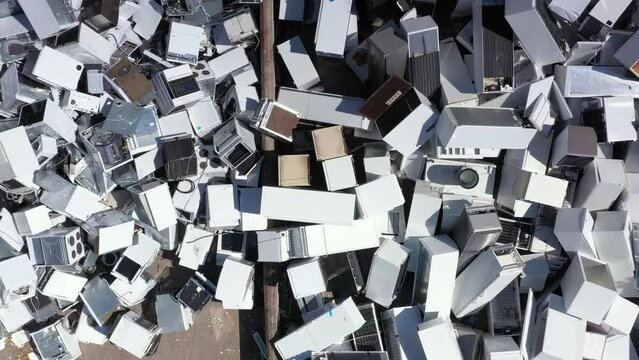 Aerial ascent above massive pile of white discarded appliances