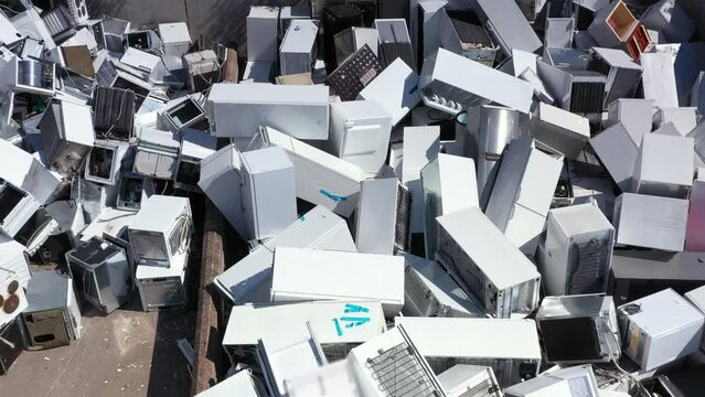 Aerial pullback view of discarded household appliances dumped at landfill