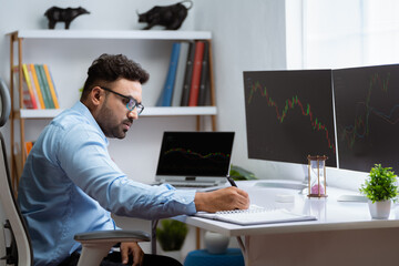 Shoulder shot of professional trader analyzing charts on monitor at office - concept of Technical Analysis, Professional investor and Risk Management