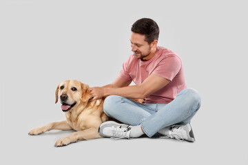 Man with adorable Labrador Retriever dog on light gray background. Lovely pet