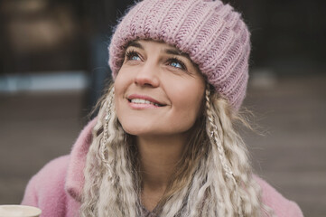 Portrait of a mature woman in a fashionable pink knitted hat. Middle aged woman positive and smiling with pigtails