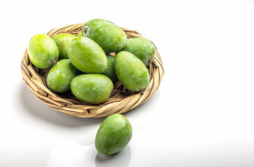 Studio shot raw mangoes kept in bamboo basket on a white background 