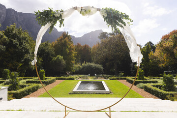Decorative wedding arch and pond in sunny garden