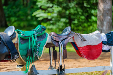 Leather saddles hang on a wooden fence. The concept of long-distance running competitions.