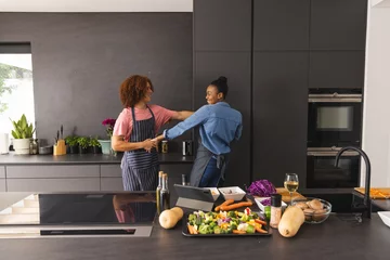  Happy diverse couple in aprons preparing meal having fun dancing in kitchen © wavebreak3