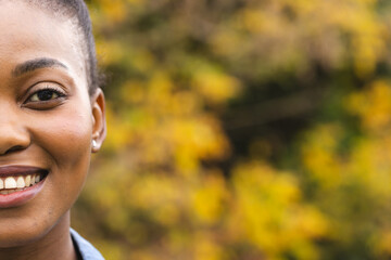 Half portrait of happy african american woman in garden smiling, copy space