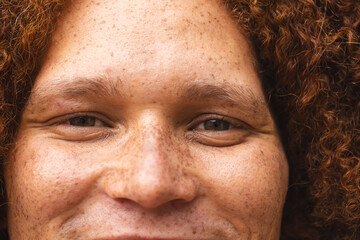 Portrait close up of happy biracial man with red curly hair and freckles smiling