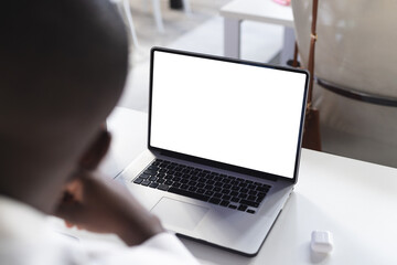 Fototapeta premium Busy african american casual businessman using laptop with copy space in office