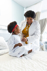 African american female doctor examining girl patient using stethoscope at hospital