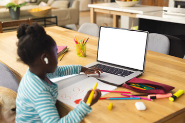 African american girl sitting at table using laptop with copy space for online lesson