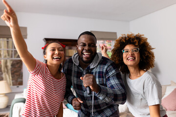 Portrait of happy diverse friends dancing and singing at home