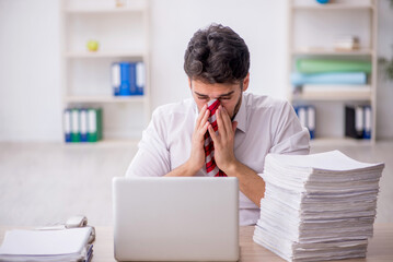 Naklejka premium Young male employee and too much work in the office