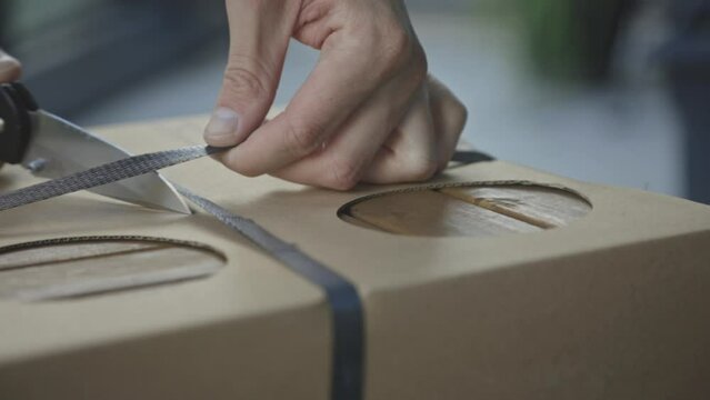 Hands Cutting Strap Of Delivery Box. Unboxing Concept. closeup
