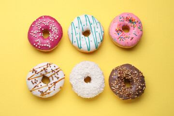 Tasty glazed donuts on yellow background, flat lay