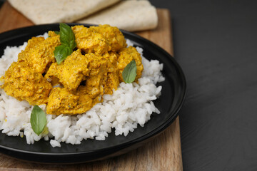 Delicious rice and chicken with curry sauce on grey wooden table, closeup. Space for text