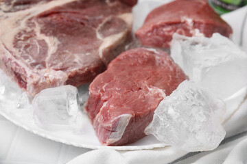 Fresh raw cut beef and ice cubes on white table, closeup