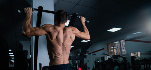 Back view of shirtless man with pull-ups in gym. 