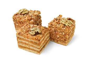 Pieces of layered honey cake with walnuts on white background