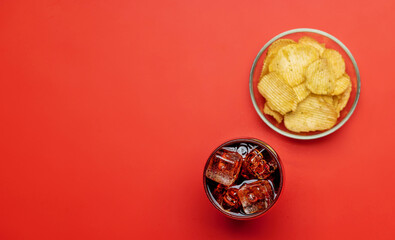 Refreshing glass of cola with ice, accompanied by a serving of crispy chips
