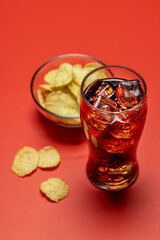 Refreshing glass of cola with ice, accompanied by a serving of crispy chips